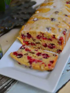 Cranberry Quick Bread in a white platter with a slice falling over