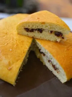 A round loaf of bread with a wedge sliced and kept on top.