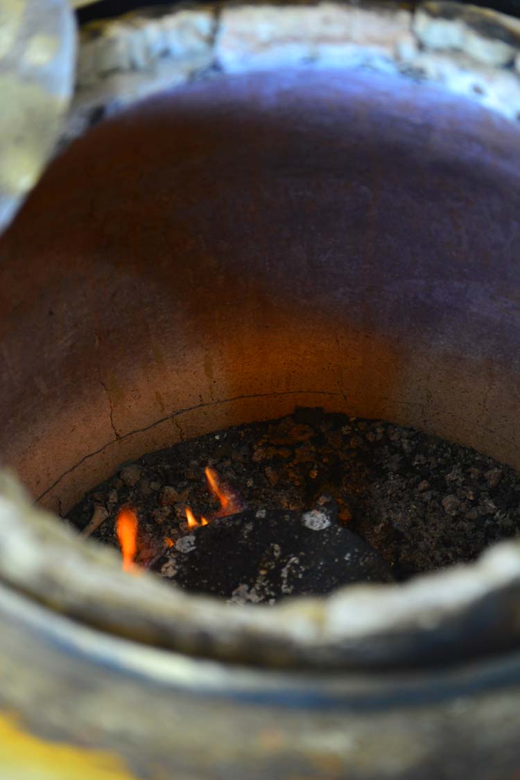 A hot tandoor with smoldering fire at the base