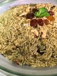 Green Chicken biriyani on a clear platter with green rim