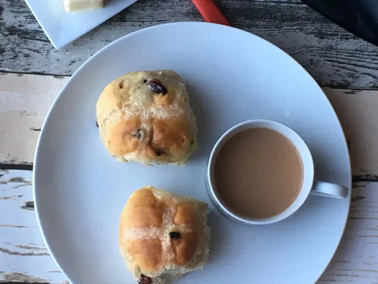 Two buns and a cup of coffee on a white plate.