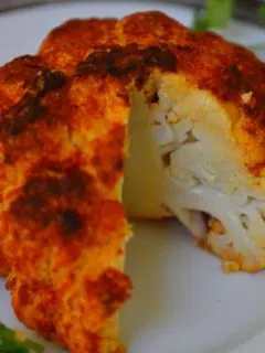 Whole Roasted Cauliflower in a plate with a slice cut off