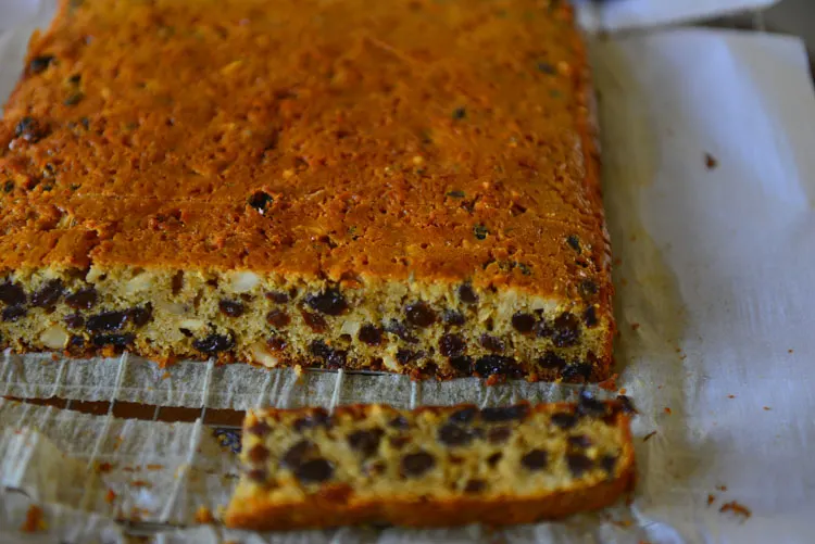 Easy Christmas Fruit Cake on a parchment sheet with a slice cut off to show the cross section
