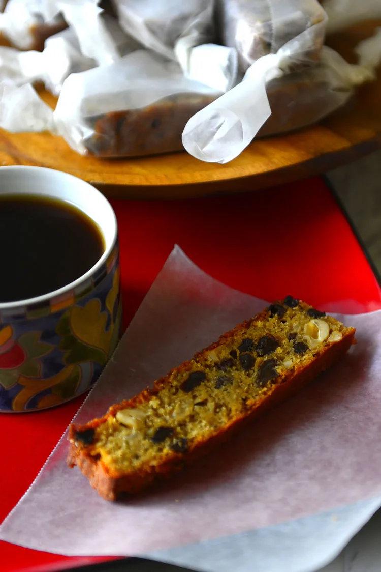 A plate with a slice of easy plum cake on a wax paper with a cup of coffee.