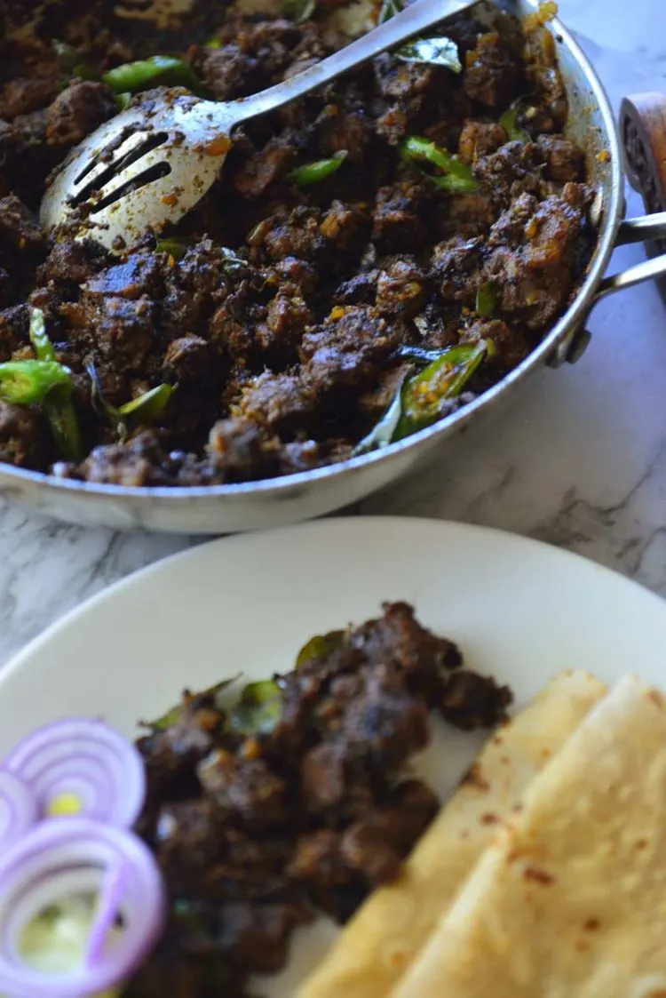 Beef fry in a pan and a plate with flat breads and beef.