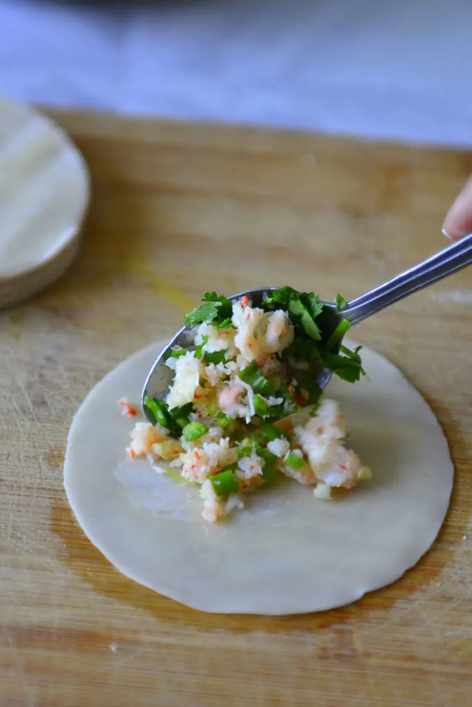 placing a  spoon-full of shrimp filling on momo wrapper / wonton wrapper 