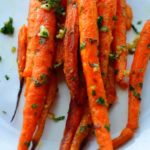 Roast carrots on a white plate - caption included. Image for pinning