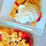 Strawberry Rhubarb Crumble topped with ice cream on a white plate with caption - Strawberry Rhubarb crumble.