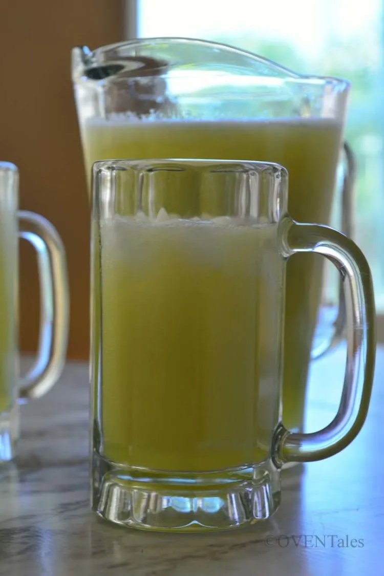 Mug of light green drink with a jar of the same drink behind it. 
