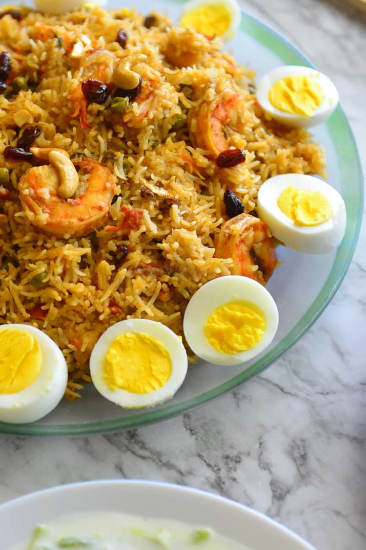 Shrimp biryani in a platterwith sliced eggs on the side.