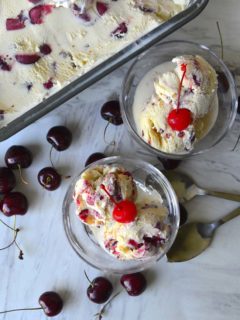 Two bowls of frozen cherry custard with a tub of custard in the background.