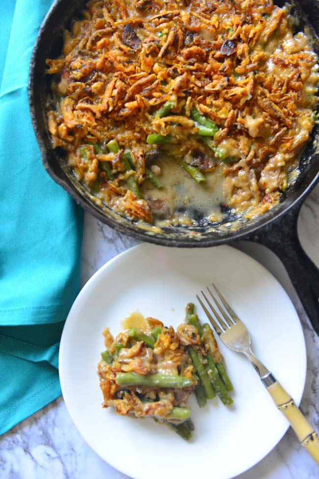 Green Bean Casserole in  a cast iron skillet  and a scoop of the same served on a white plate and a  fork. 