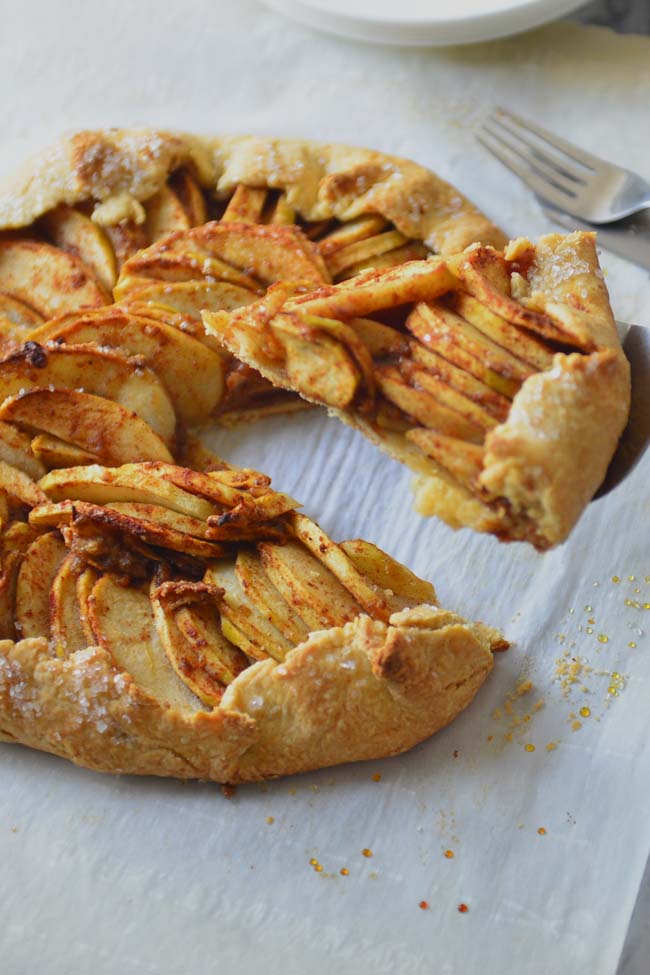 Apple galette on a parchment paper  with a lice  on pie server 
