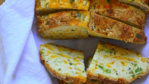 Sliced Green Onions and cheese soda bread in a bread basket .