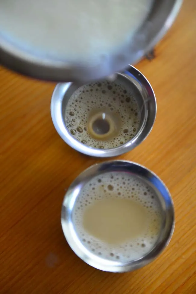 Pouring Milk over the thick dark decoction to make filter coffee