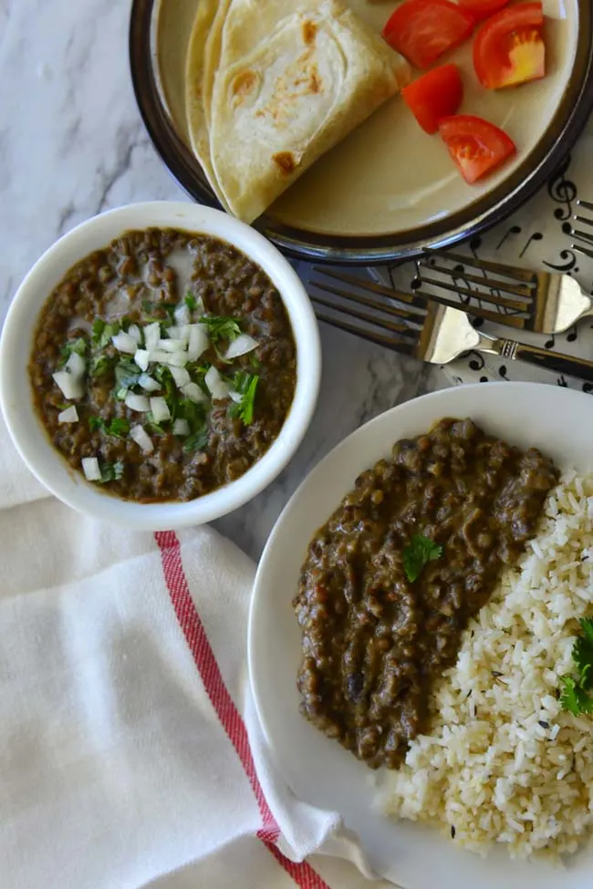 Plate with lentils and rice, a bowl of lentils and plate with roti and veggies .