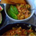 Image for pinning - a bowl with menemen and slices of avocado and toast with a pan with egg scramble next to it.