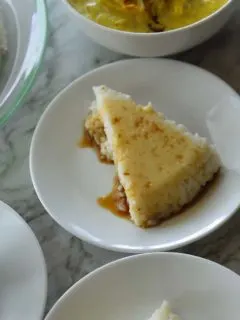 A slice of Vishu Katta on a white plate with syrup over it.