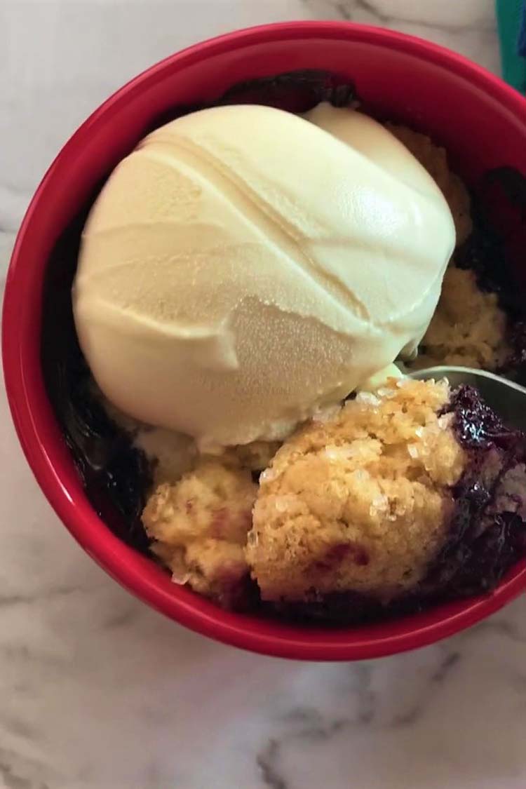 Scooping a spoonful of blueberry cobbler from an individual serving bowl