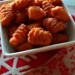 A bowl of kulkuls on table decorated for Christmas - Caption 'kulkul- Fried Sweet Curls'