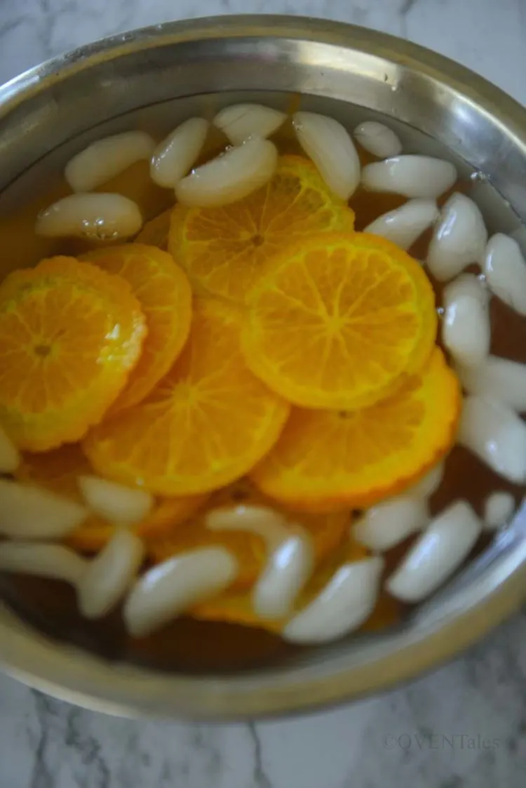 Boiled orange slices in a bowl of cold water with ice.