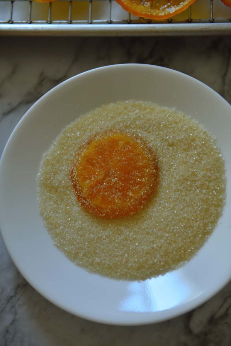 Plate of sugar with a candied orange slice on top of the sugar.