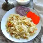 Garbanzo beans pilaf on a plate with a bowl of raita. Image with caption ' Chickpea Pilaf - Instant Pot version'. Image for Pinning