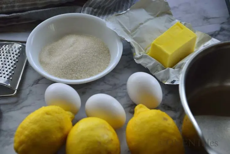 lemon, eggs, butter, sugar, zester and a pan.