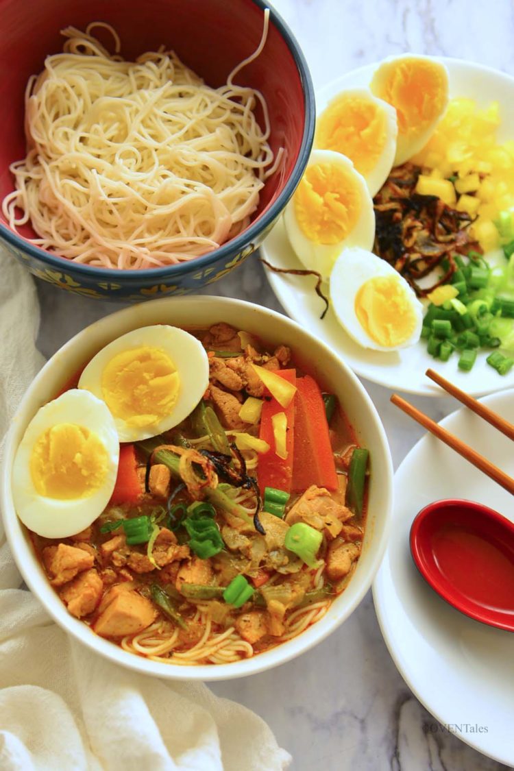 A bowl of noodle, a bowl of soup and various accompaniments. 